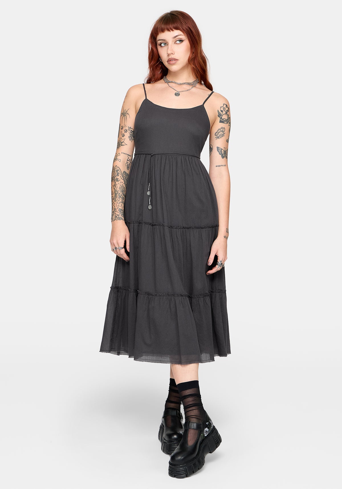 Woman wearing a grey tiered dress on a white background
