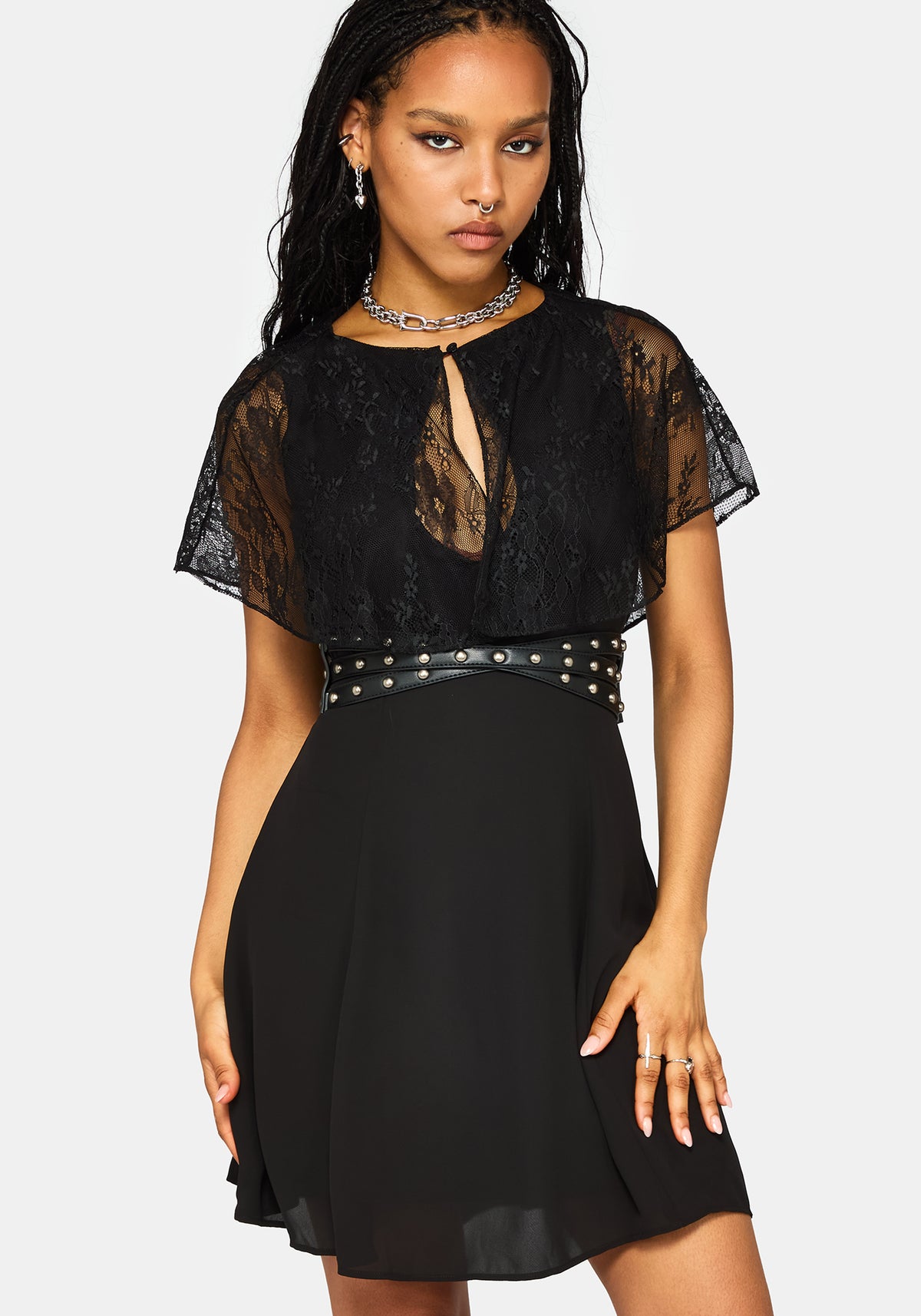 A woman modeling a black lace and chiffon mini dress with a studded waist belt, against a light gray background.