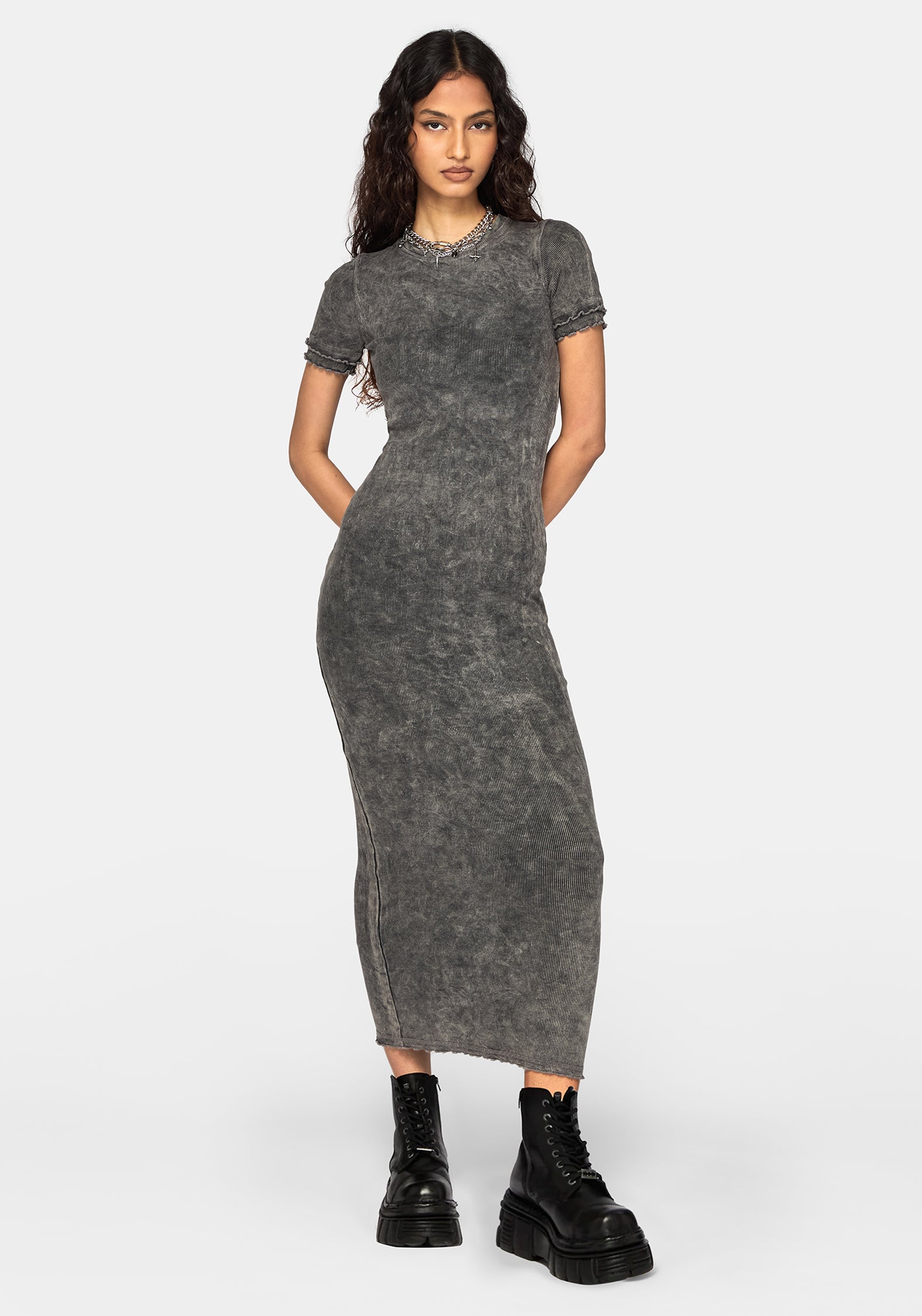 A woman modeling a short-sleeve, high-neck, bodycon midi dress in a washed charcoal gray color, styled with black combat boots against a light gray studio background.