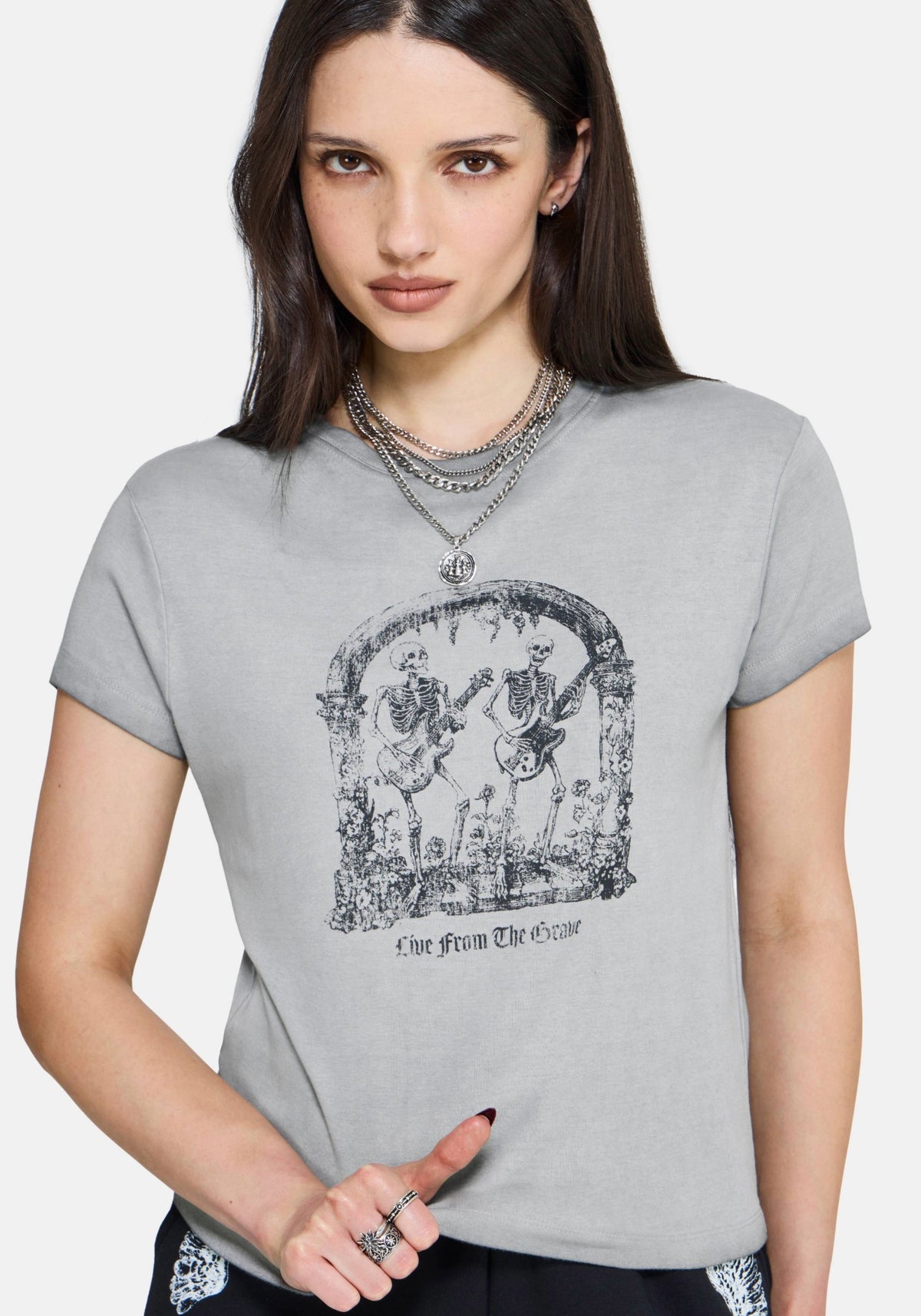 Woman wearing a gray t-shirt with a graphic design of skeletons playing music.