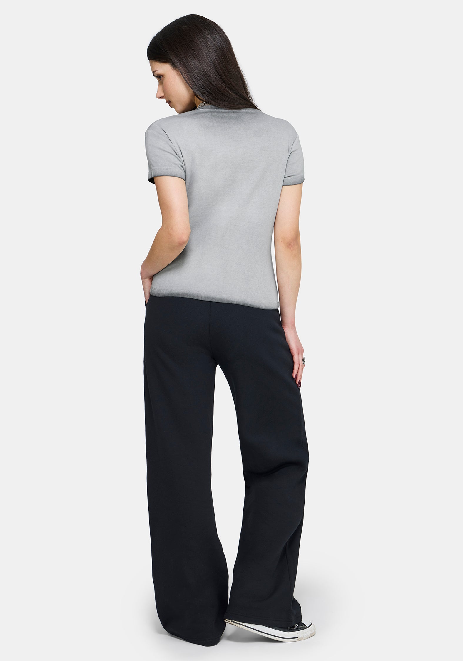 Woman wearing a gray t-shirt and black pants on a white background