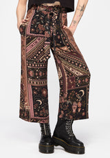 Person wearing patterned culottes and black boots on a white background
