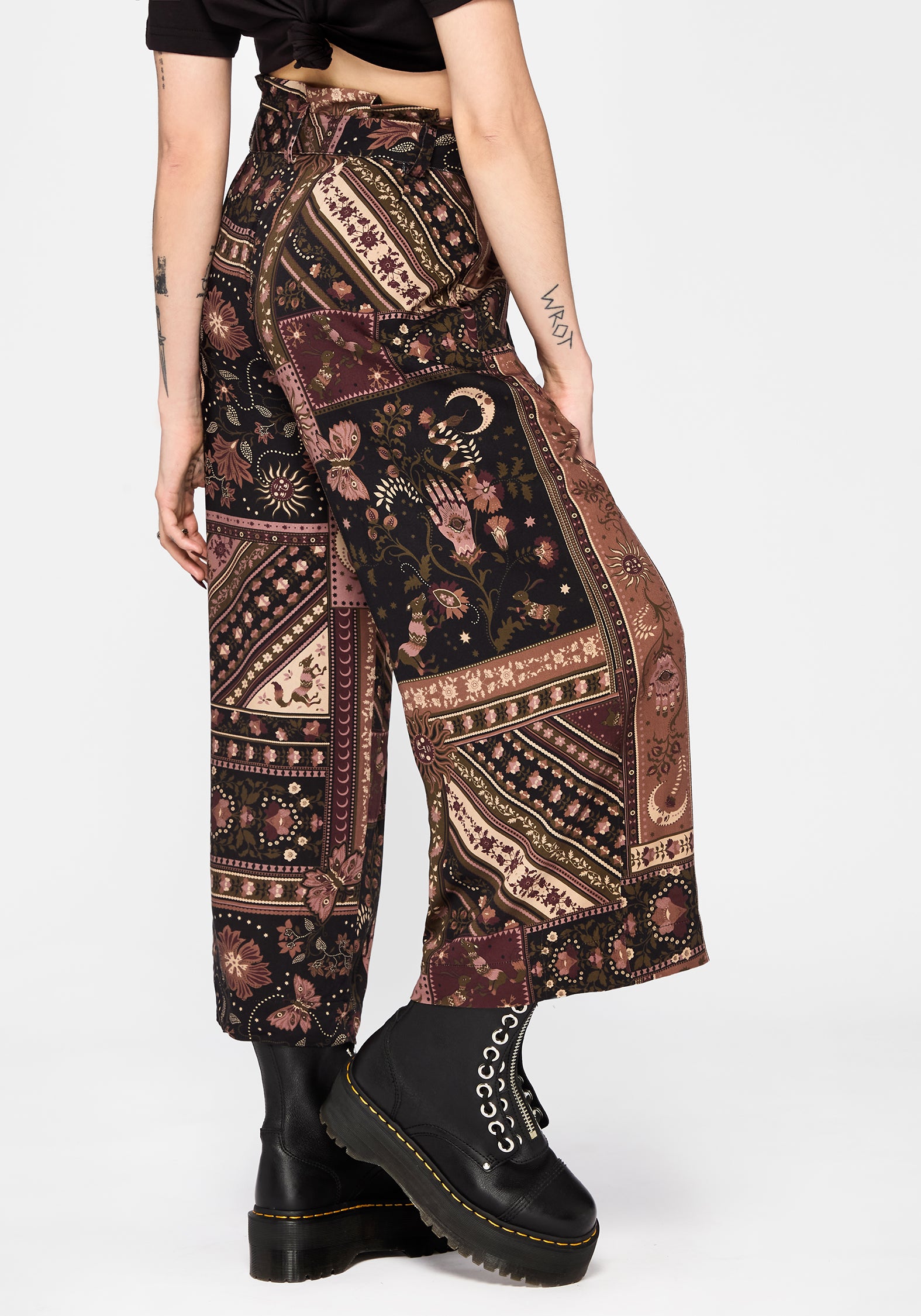 Person wearing patterned wide-leg culottes and black boots on a white background